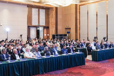 People sitting in a large room looking towards the camera