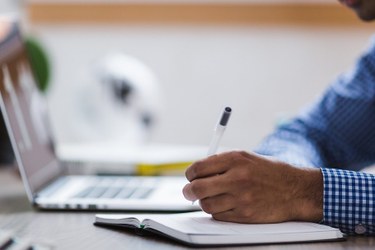 A person sitting at a desk writing on a paper