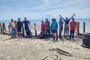 A group of people on the beach with a banner