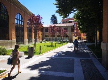 Cortile alberti con una persona che cammina ed una in bicicletta